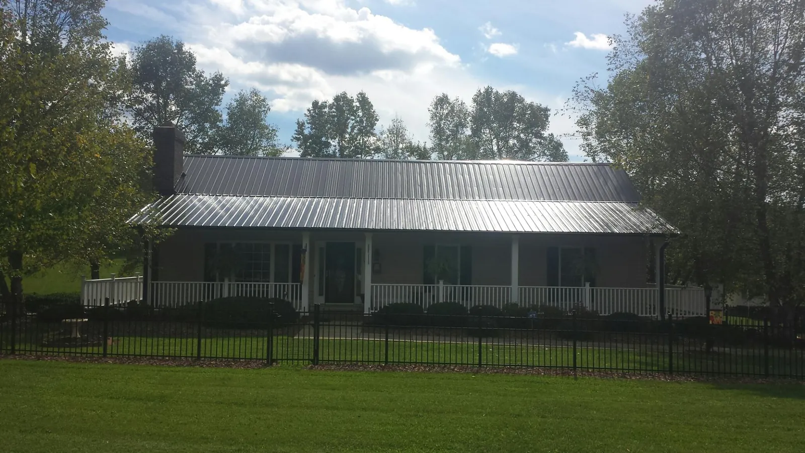 Gray metal roof on a brick ranch with a full width front porch — Gutter Guard Installation work by our crew in West Long Branch