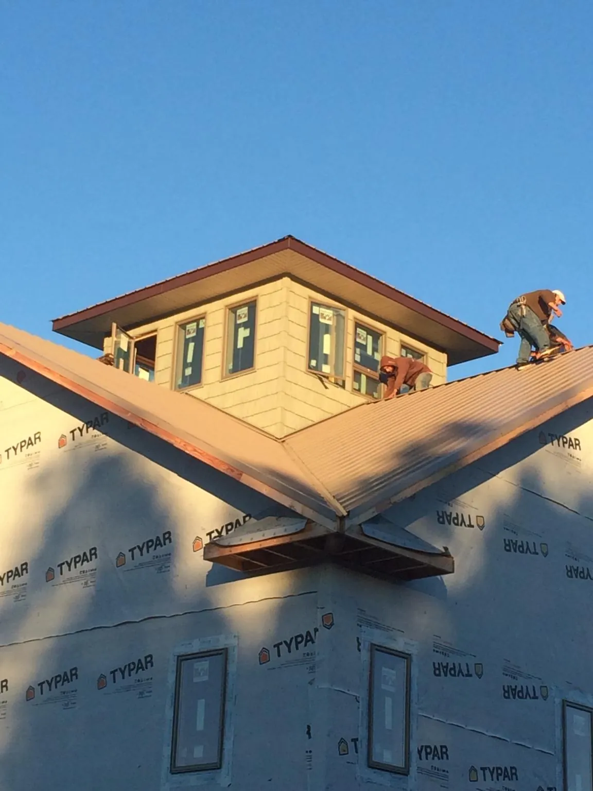 Roofers working around a rooftop cupola on a new metal roof at sunset — Roof Waterproofing in West Long Branch by Roofing Brothers